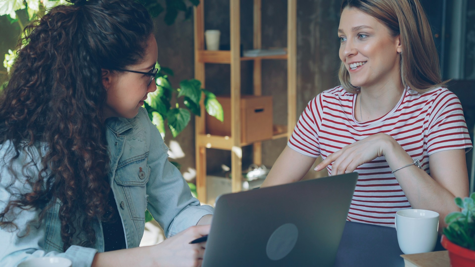 Two women work together on a laptop.